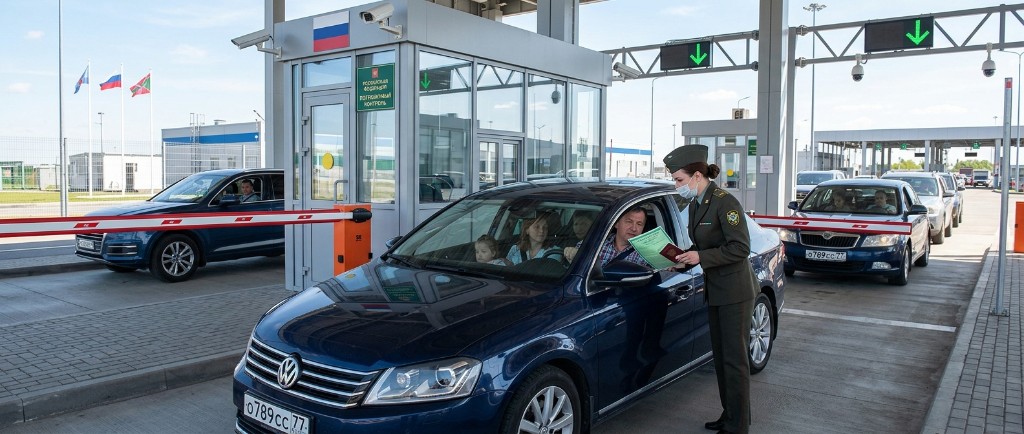 Пограничный контроль на въезде в Россию — таможенник проверяет полис ОСАГО и паспорт у водителя на пропускном пункте